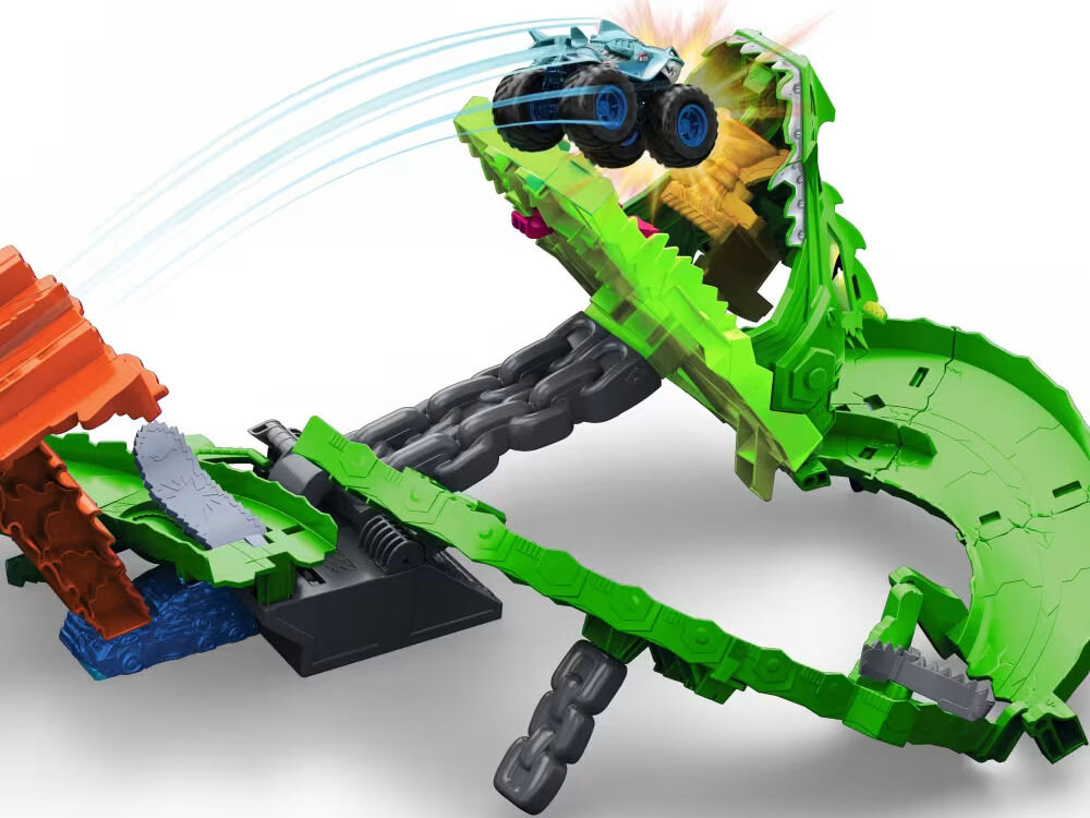 Samochód zdalnie sterowany Hot Wheels Tiger Shark HNV03 Zbliżenie na tor Hot Wheels Monster Trucks Dragon Arena w trakcie akcji. Niebieski samochód monster truck z motywem rekina wyskakuje z pomarańczowej rampy i leci w kierunku otwartej paszczy zielonego smoka, z której wydobywa się blask. Tło jest białe.