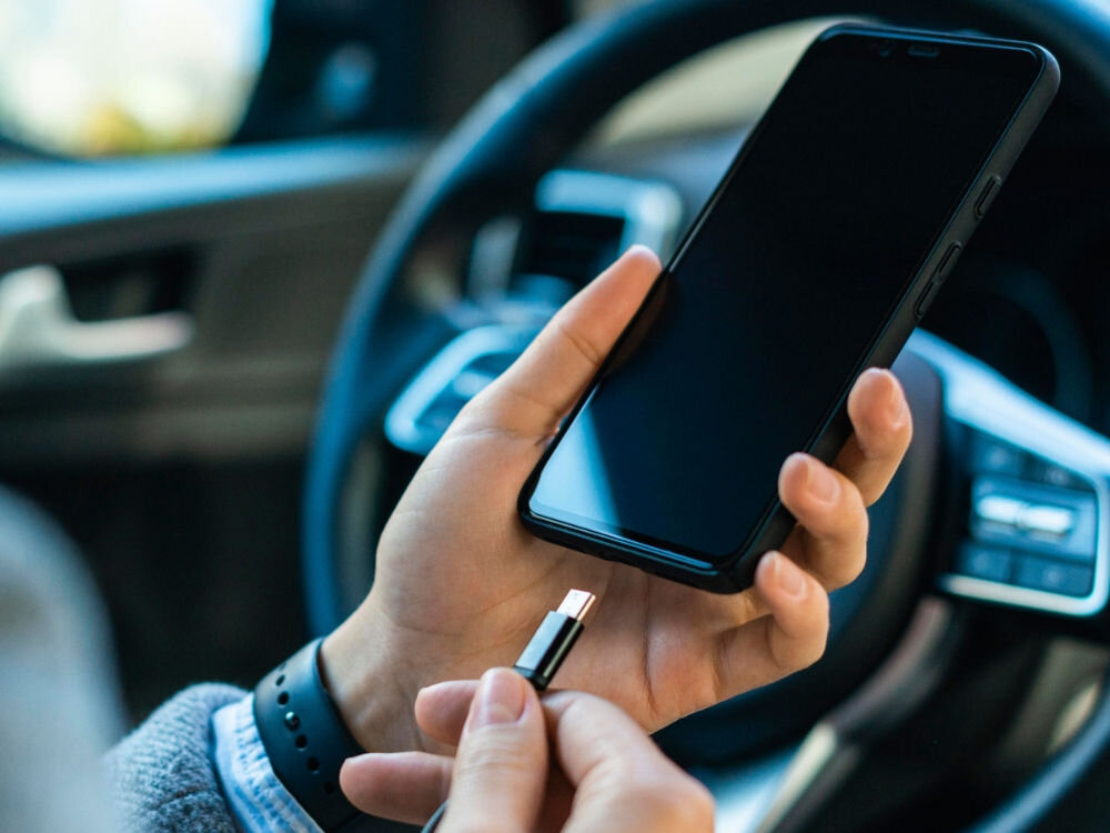 Ładowarka samochodowa MOTOROLA TurboPower 45W Czarny
                telefon w dłoni podczas podłączania kabla w samochodzie