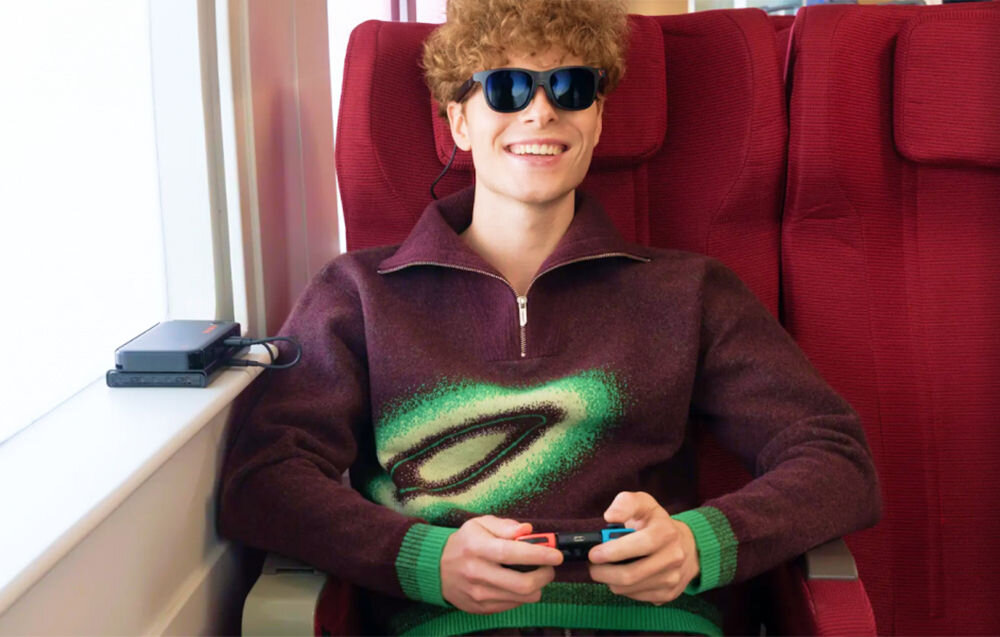 Okulary VITURE Pro XR Czarny prezentacja okularów podczas użytkowania przez chłopaka siedzącego w pociągu grającego na przenośnej konsoli elektrochromowa folia blokująca 99,9% światła zewnętrznego skupienie na wyświetlanej treści