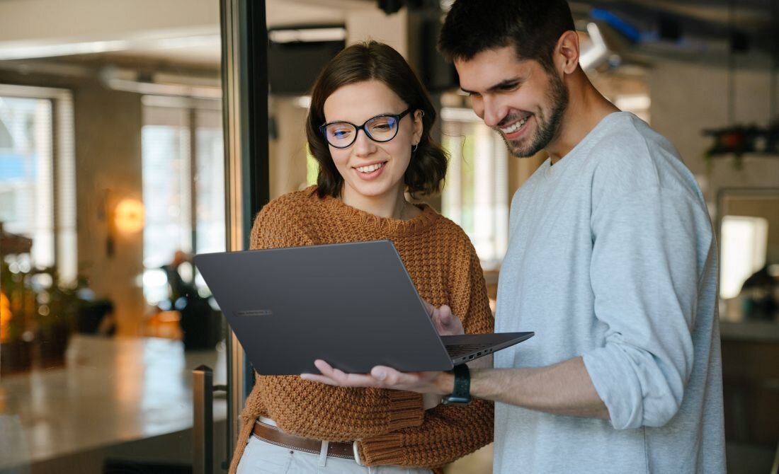 ASUS ExpertBook B1 użytkowany przez dwóch uśmiechniętych profesjonalistów w nowoczesnym biurze, demonstrując lekkość i mobilność urządzenia - lekki laptop 