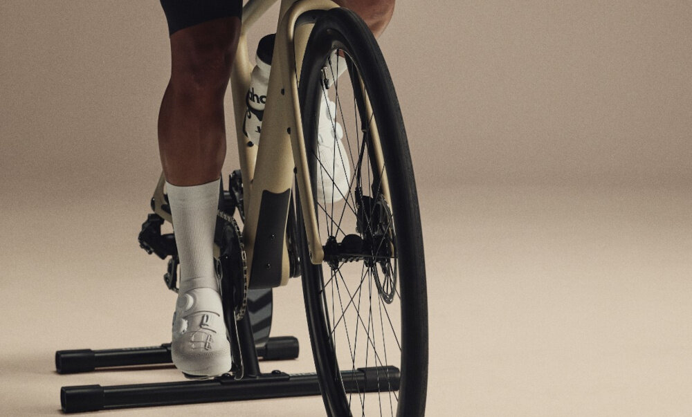 Trenażer rowerowy WAHOO Kickr Core 2 WFBKTR125-11S1128 jasnobrązowe tło osoba jedzie na rowerze podłączonym do trenażera bezprzewodowe aktualizacje oprogramowania przez Wahoo Fitness App lub Wi-Fi współpracuje z wieloma platformami i aplikacjami treningowymi