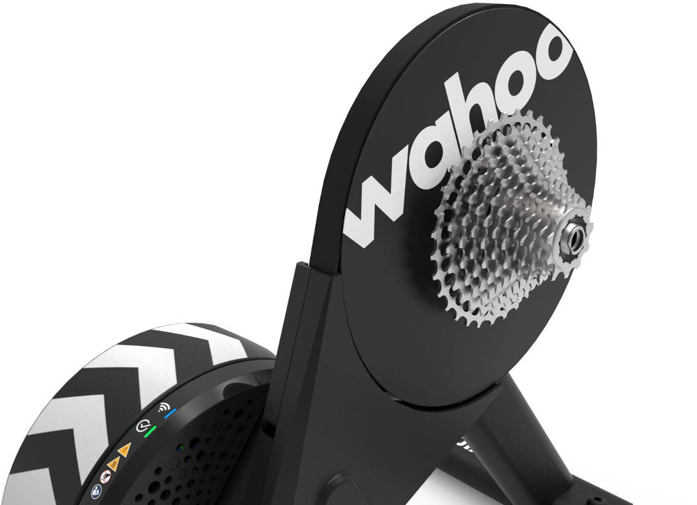 Trenażer rowerowy WAHOO Kickr Core 2 WFBKTR125-11S1128 trenażer na białym tle widoczny od góry zbliżenie na kasetę funkcja KICKR Bridge dane z monitorów tętna przesyłane są bezpośrednio do aplikacji przez trenażer centralna jednostka dla czujników wbudowany sensor kadencji obsługuje rowery z mocowaniem 130/135 mm QR oraz osiami 12×142 i 12×148 prześwit na hamulec tarczowy montaż różnych modeli rowerów stabilność konstrukcji