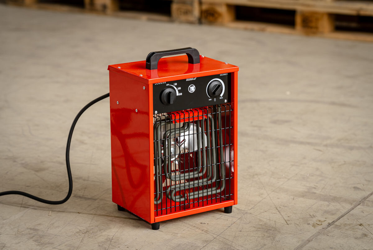 Nagrzewnica elektryczna DEDRA DED9921, 3300W, komfort, garaż, trzy tryby, Nagrzewnica DEDRA DED9921 na tle magazynu, podłączona, gotowa do pracy, czarna rączka.