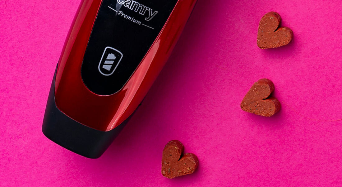 Czerwona maszynka z napisem \'camry Premium\' na różowym tle. Obok znajdują się cztery serduszka w kolorze brązowym.