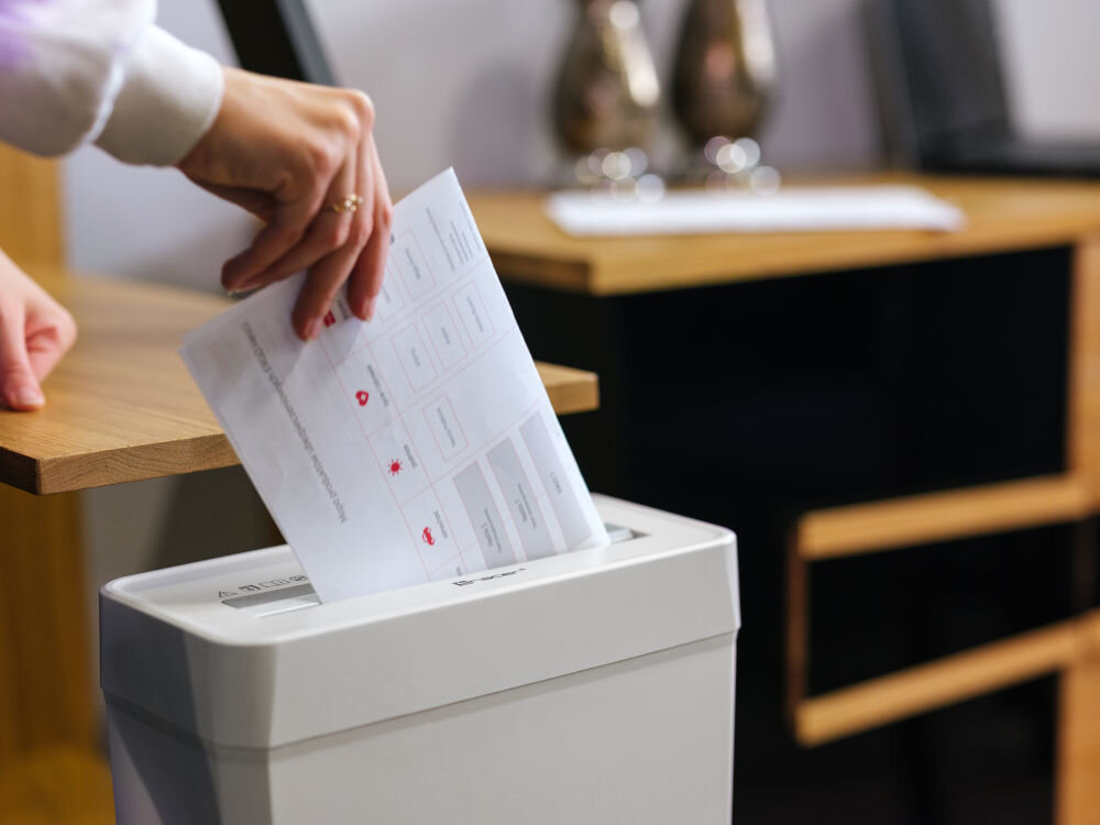 Niszczarka TRACER Razor 3 10 L, P-2, Paski, Automatyczny Start/Stop, Funkcja cofania Biały prezentacja niszczarki podczas korzystania osoba wkładająca papier do niszczarki stojącej przy biurku w pokoju biuro dom ochrona prywatności wygoda użytkowania