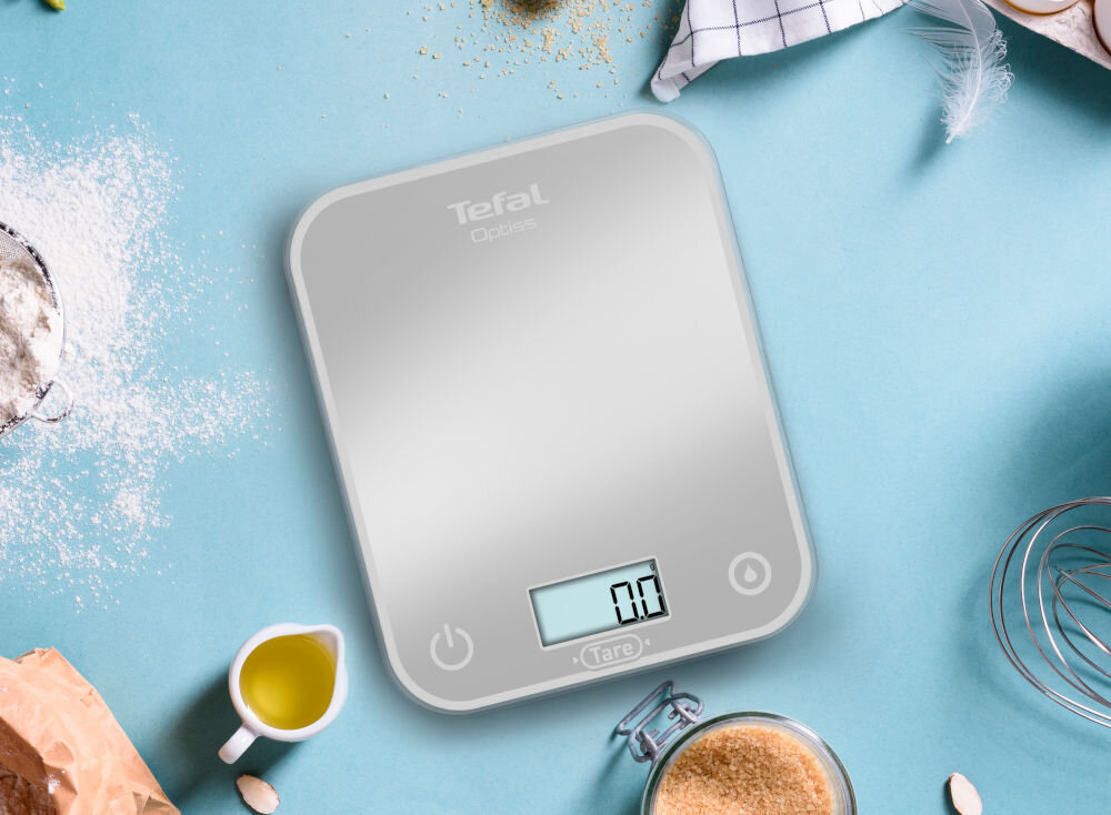 Waga kuchenna TEFAL BC50U4V0 niebieskie tło waga srebrny kolor przyciski świecący wyświetlacz kuchenny sprzymierzeniec precyzyjność praktyczne podejście dokładność pomiaru do 0,5 g funkcjonalne narzędzie w kuchni 