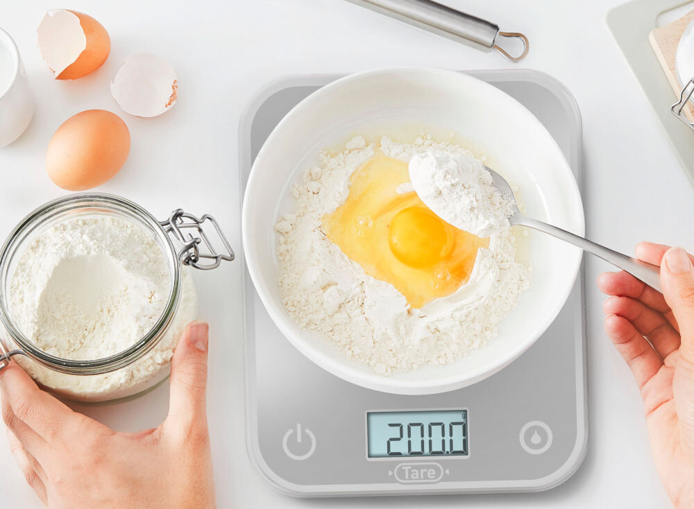 Waga kuchenna TEFAL BC50U4V0 waga na wadze miska w misce znajdują się składniki ręka dosypuje składniki wyświetlacz przyciski funkcja tarowania dokładne ważenie składników proste naciśnięcie przycisku zresetowanie wagi dodanie kolejnych produktów usprawnienie przygotowywania złożonych potraw sprytne rozwiązanie oszczędność czasu utrzymanie porządku dopracowanie smaku i konsystencji dla entuzjastów gotowania mistrzów kuchni 