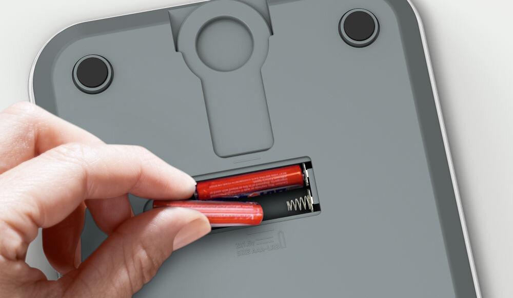 Waga kuchenna TEFAL BC50U4V0 ręcę wkładają baterię do wagi 2 baterie jasne tło zasilanie 2 bateriami AAA gotowa do działania po rozpakowaniu płynność w kuchni szybkie rozpoczęcie pracy 