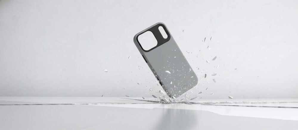 Szare etui do iPhone 17 Pro uderza o podłoże, rozbijając białą powierzchnię na odłamki, co symbolizuje ochronę przy upadku.