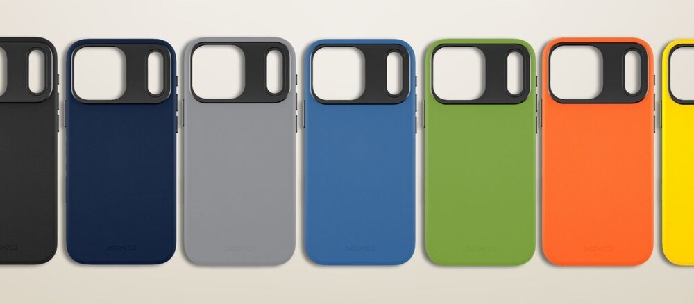 Zielone etui do iPhone 17 Pro Max leży na jasnej, teksturowanej tkaninie obok ciemnego długopisu i małego notesu z napisem „day by day”