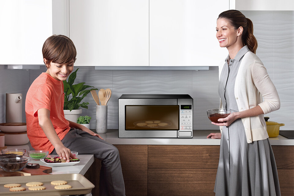 Matka z dzieckiem przygotowująca deser w kuchence mikrofalowej