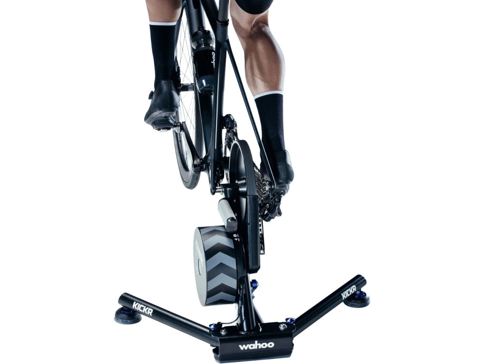 Trenażer rowerowy WAHOO Kickr Smart Trainer V6 WFBKTR122 białe tło osoba jedzie na rowerze rower umieszczony na trenażerze widok od tyłu wskaźnik wyeksploatowania wizualne diody LED bezpieczeństwo użytkowania pomaga w planowaniu przeglądów i serwisowania urządzenia