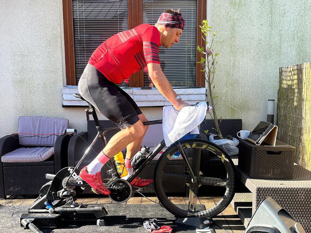 Trenażer rowerowy WAHOO Kickr Move Power Trainer WFBKTR123 taras osoba jedzie na rowerze rower umieszczony na trenażerze współpracuje z osiami 12x142, 12x148 i standardowymi szybkozamykaczami 130/135 mm uniwersalność sprzętu intuicyjna aplikacja Wahoo Fitness