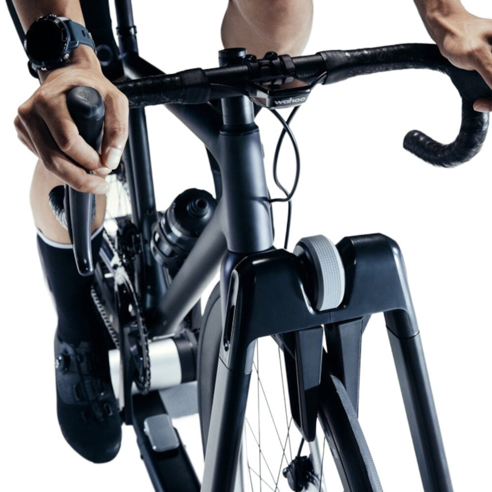 Trenażer rowerowy WAHOO Kickr Rollr Smart Trainer V2 WFBKTR9B białe tło osoba jedzie na rowerze rower umieszczony na trenażerze można szybko ustawić przednie koło w uchwycie tylne na rolkach regulacja rozmiaru i możliwość zmiany roweru pasuje do różnych typów rowerów