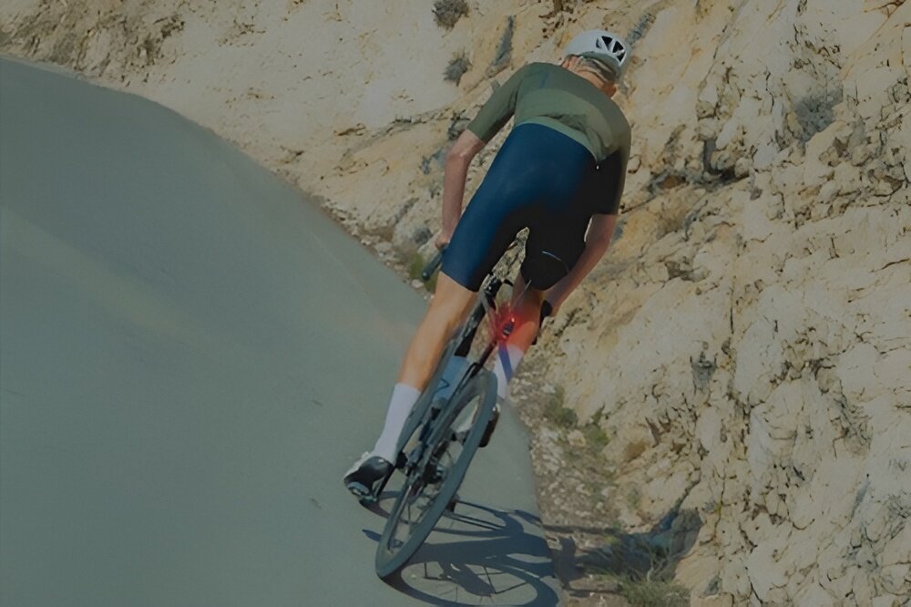 Wsteczny radar rowerowy WAHOO TrackR Radar Smart WFTRACKRRDR1 droga ulica osoba jedzie na rowerze zbliżenie na radar umieszczony pod sztycą siodełka wbudowany akcelerometr wykrywa moment zwalniania i automatycznie zwiększa jasność światła kierowcy jadący z tyłu szybciej zauważają zmianę tempa rowerzysty poprawia płynność jazdy w grupie i zwiększa bezpieczeństwo