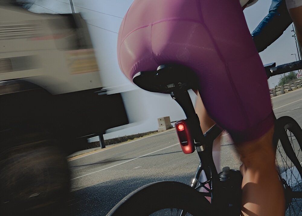 Wsteczny radar rowerowy WAHOO TrackR Radar Smart WFTRACKRRDR1 miasto droga ulica osoba jedzie na rowerze zbliżenie na radar umieszczony pod sztycą siodełka obudowa spełniająca normę IPX7 ochrona przed wodą wytrzymałość konstrukcji odpowiada za dłuższą żywotność