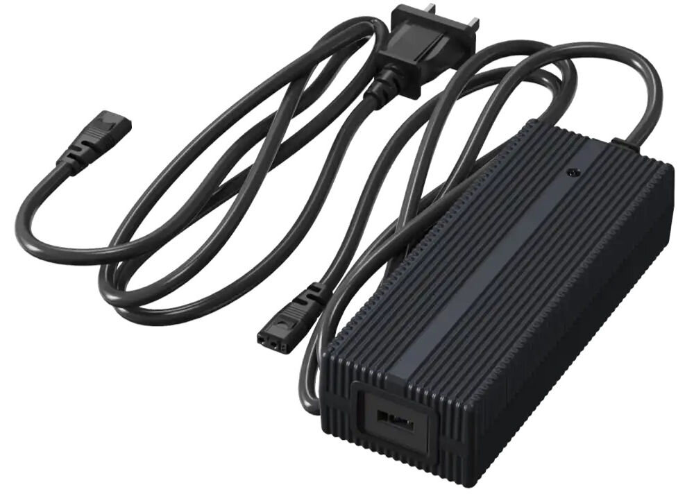 Ładowarka UNITREE Go2 Fast Charge Zdjęcie studyjne, przedstawiające czarną, prostokątną ładowarkę sieciową do robota Unitree. Obok zasilacza leży dołączony, zwinięty kabel zasilający z wtyczką typu G (UK/Irlandia) oraz drugi, mniejszy kabel zasilający.