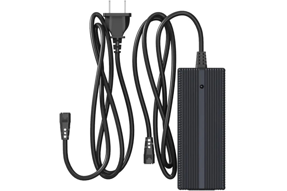 Ładowarka UNITREE Go2 Fast Charge Zdjęcie studyjne, przedstawiające czarną, prostokątną ładowarkę sieciową (zasilacz) do robota Unitree, ułożoną pionowo. Widoczny jest długi, czarny kabel z wtyczką do robota oraz dołączony, zwinięty kabel zasilający z wtyczką typu G (UK/Irlandia).