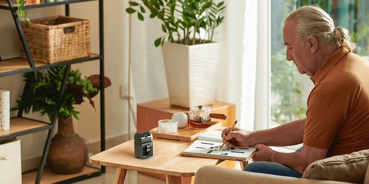 Kamera IMOU Rex VT Pro Wewnętrzna, Wi-Fi, obraz, ochrona, bezpieczeństwo, nadzór, mężczyzna w pokoju czyta gazetę, na stole stoi kamera imou