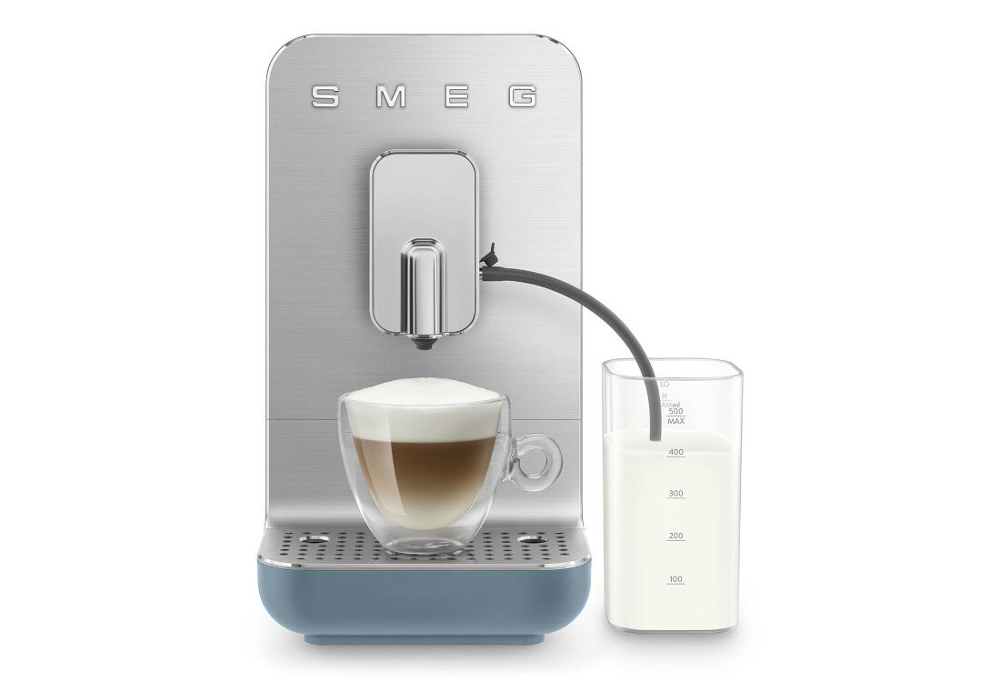 Ekspres do kawy SMEG w kolorze srebrno-niebieskim z filiżanką kawy i pojemnikiem na mleko. Na ekspresie widoczne jest logo \'SMEG\'.