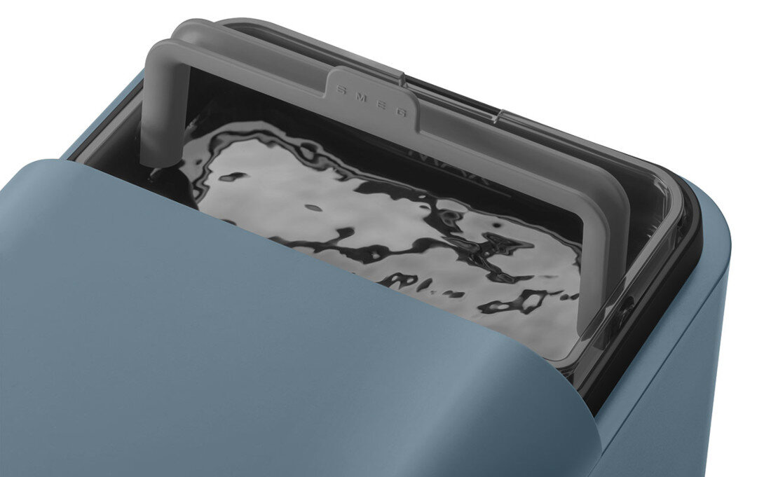 Zbliżenie na górną część ekspresu do kawy w kolorze srebrno-niebieskim z widocznym logo \'SMEG\'. Widać przezroczysty pojemnik z wodą na górze urządzenia.