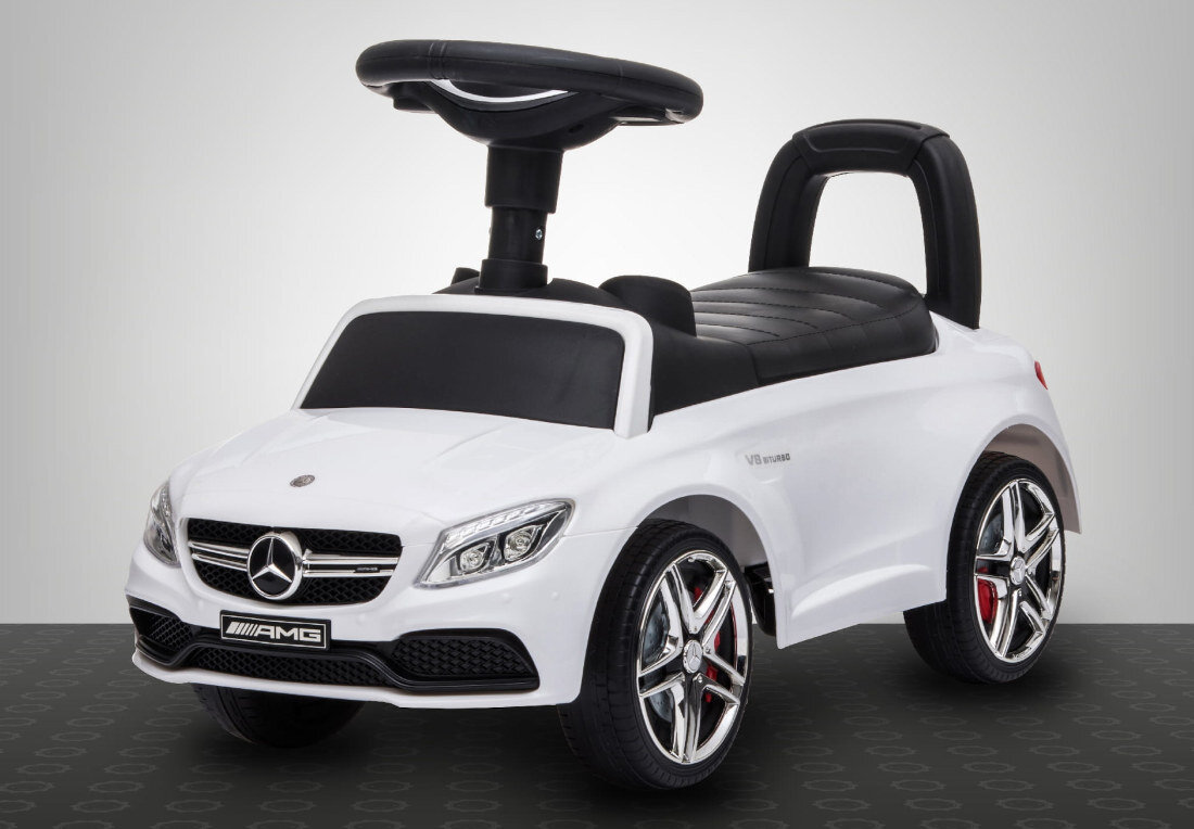 Biały jeździk w kształcie samochodu z logo Mercedes na przodzie i napisem AMG na tablicy rejestracyjnej. Posiada czarne siedzenie i kierownicę oraz srebrne felgi z czerwonymi elementami.