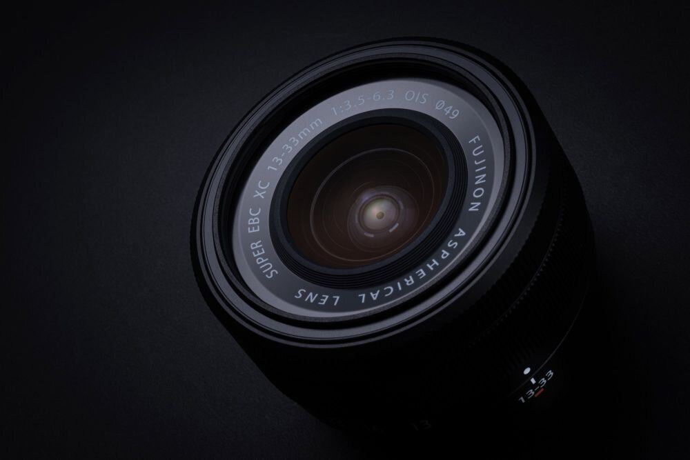 Obiektyw fotograficzny z widocznymi napisami: \'FUJINON ASPHERICAL LENS SUPER EBC XC 13-33mm 1:3.5-6.3 OIS Ø49\'.