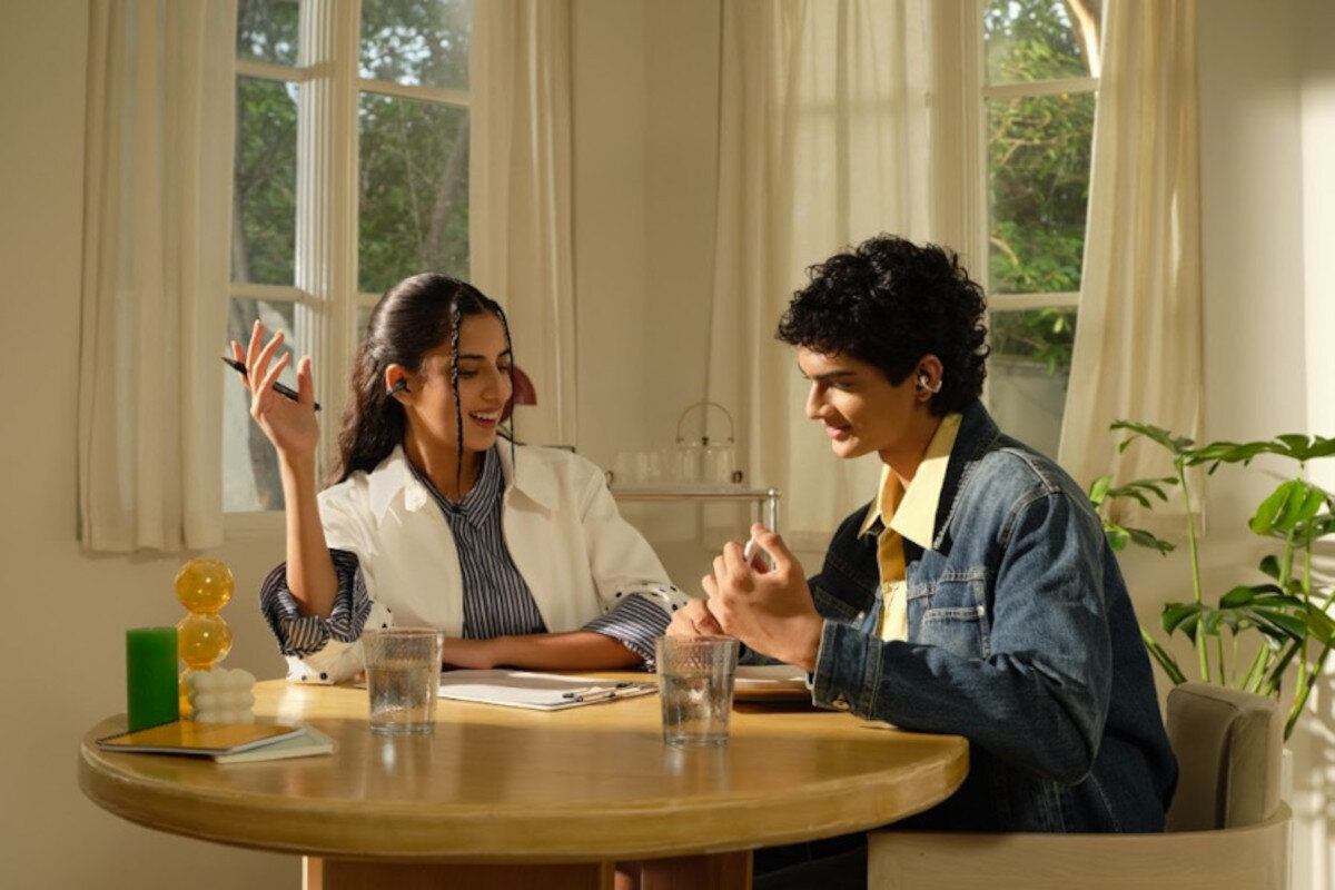 REALME Buds Clip tłumaczenie AI Bluetooth 5.4 sterowanie dotykowe wygoda funkcje inteligentne, osoby siedzące przy stoliku z założonymi słuchawkami powietrznymi