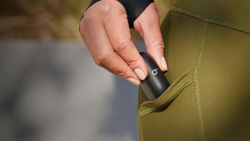 Słuchawki dokanałowe BEATS Solo Buds otwory wentylacyjne laserem, lepsze brzmienie basów, komfort, osoba wkładjąca etui ładujące do kieszeni