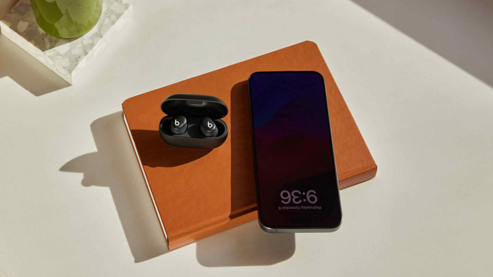 Słuchawki dokanałowe BEATS Solo Buds kompatybilność iOS Android, automatyczne parowanie, funkcje Znajdź, słuchawki dokanałowe z etui ładującym oraz smartfonem leżące na notesie