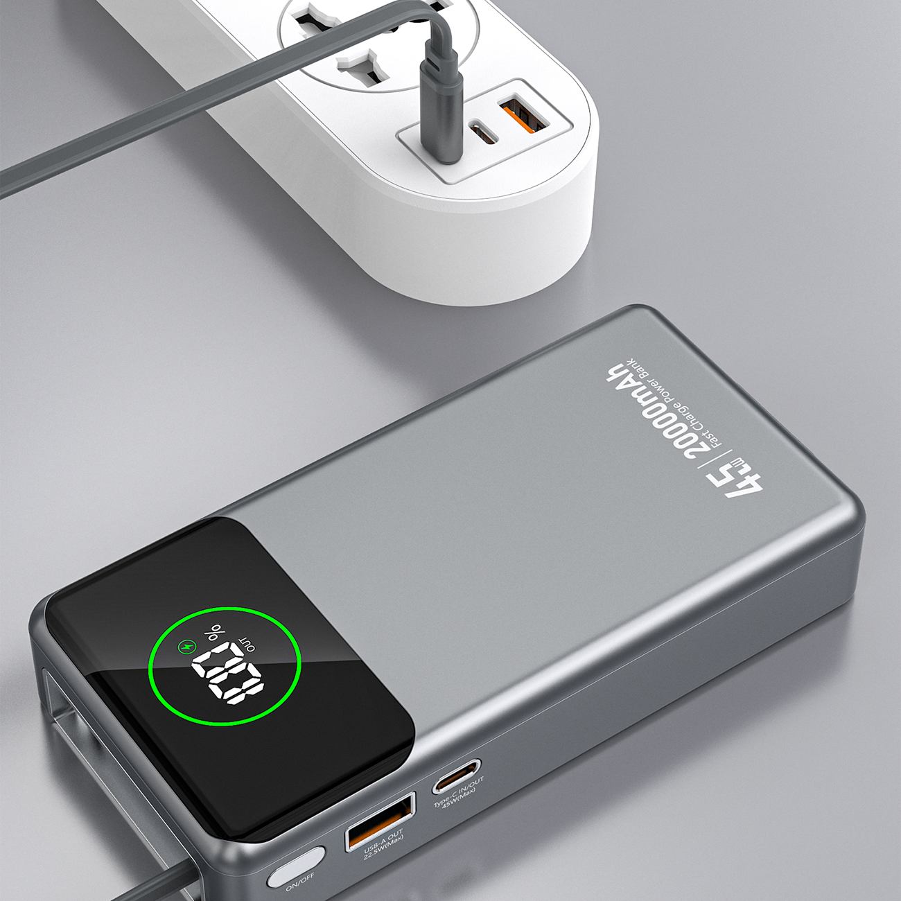 Szary powerbank z wyświetlaczem pokazującym 75% naładowania, obok znajduje się biała listwa zasilająca z podłączonym kablem. Na obudowie powerbanka widoczny jest napis \'45W 20000mAh\'.