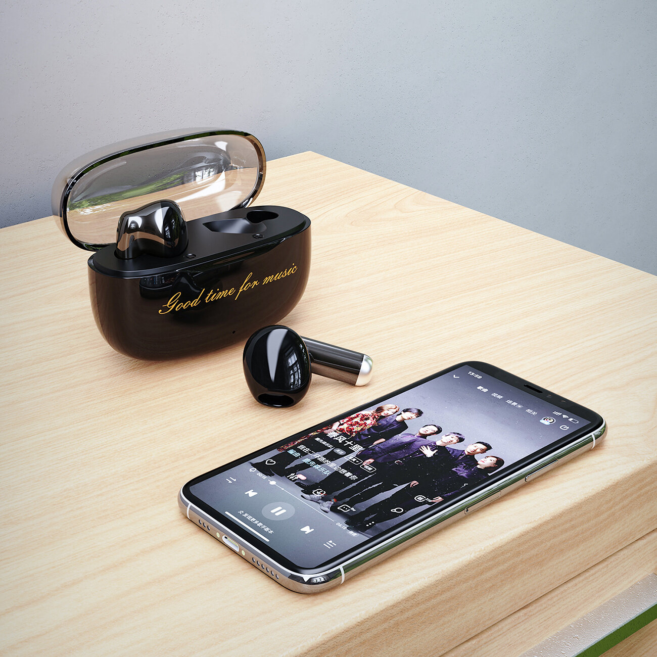 Na drewnianym blacie znajdują się czarne słuchawki bezprzewodowe z etui, na którym widnieje napis \'Good time for music\'. Obok leży smartfon z włączoną aplikacją muzyczną, na ekranie widoczny jest zespół muzyczny.