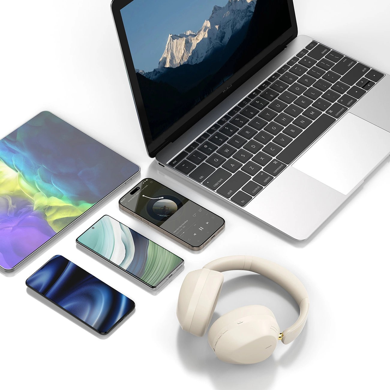 Na obrazie widoczny jest laptop z otwartym ekranem, trzy smartfony, tablet oraz beżowe słuchawki nauszne. Ekran laptopa wyświetla krajobraz górski, a na jednym ze smartfonów widoczny jest interfejs odtwarzacza muzyki.