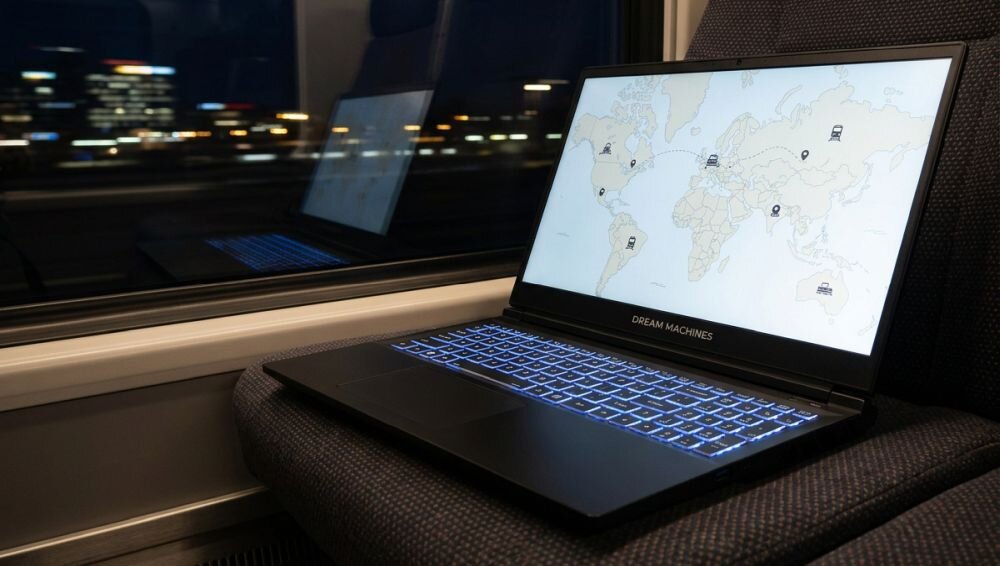Laptop Dream Machines z podświetlaną klawiaturą wyświetla mapę świata podczas pracy mobilnej w pociągu nocą  