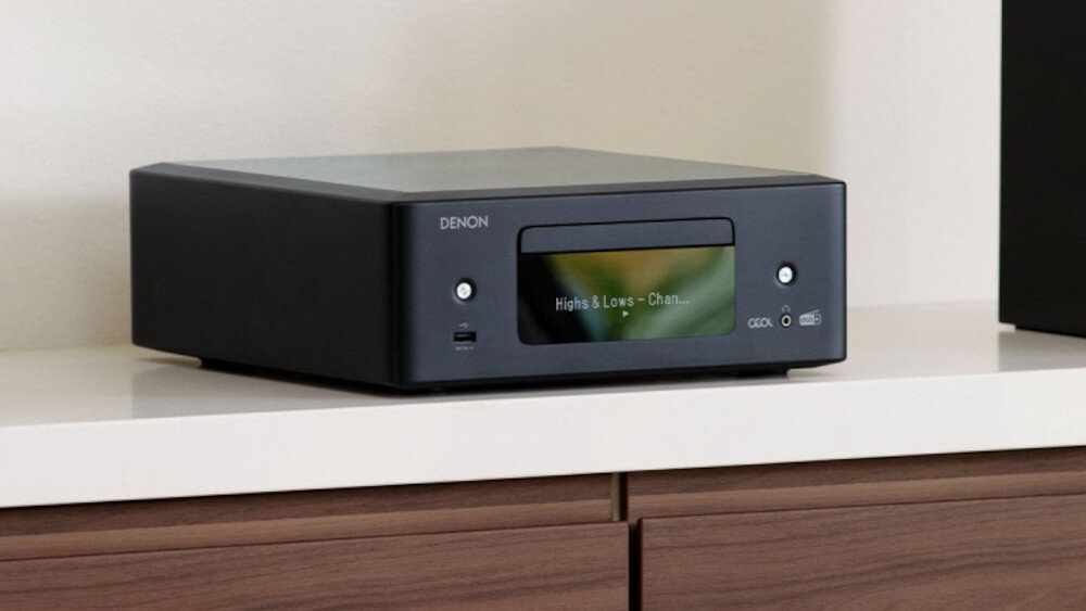 Czarny amplituner stereo z wyświetlaczem, na którym widoczny jest tekst \'Highs & Lows - Chan...\'. Na urządzeniu znajduje się logo \'DENON\'.