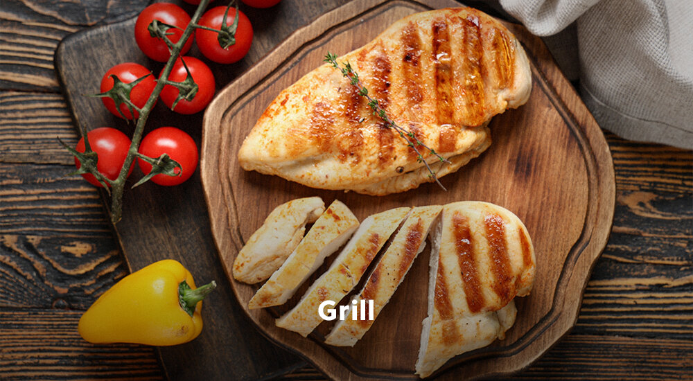 KUCHNIA MIKROFALOWA BEKO BMGB31443B  Na drewnianej desce leży opieczona pierś z kurczaka z wyraźnymi paskami z grilla, częściowo pokrojona w plastry. W tle widoczne są pomidorki koktajlowe na gałązce i żółta papryka, a na środku napis „Grill” grill w mikrofali chrupiąca skórka przyrumienienie kurczak ryba warzywa
