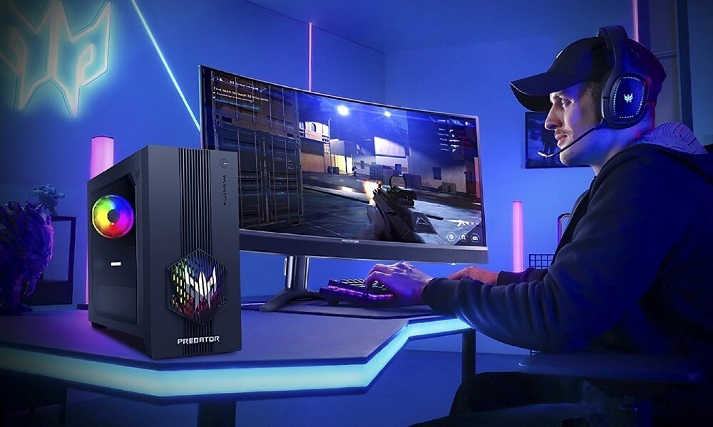 Komputer ACER Predator Orion 3000 PO3-665 Mężczyzna w słuchawkach z mikrofonem siedzi przy biurku i gra na zakrzywionym monitorze, obok którego stoi komputer z podświetleniem RGB, przeznaczenie, cechy