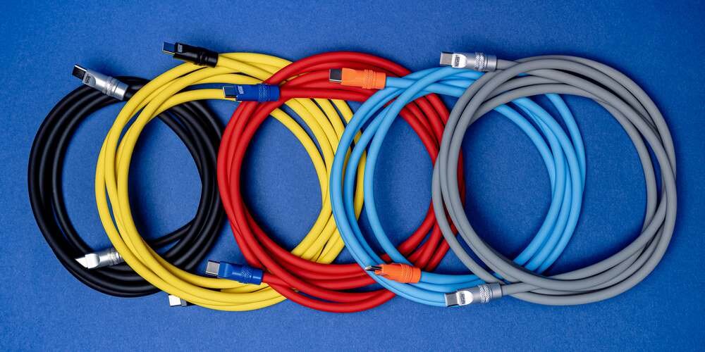 Pięć różnokolorowych kabli silikonowych Newell na niebieskim tle złożonych i nachodzących na siebie.