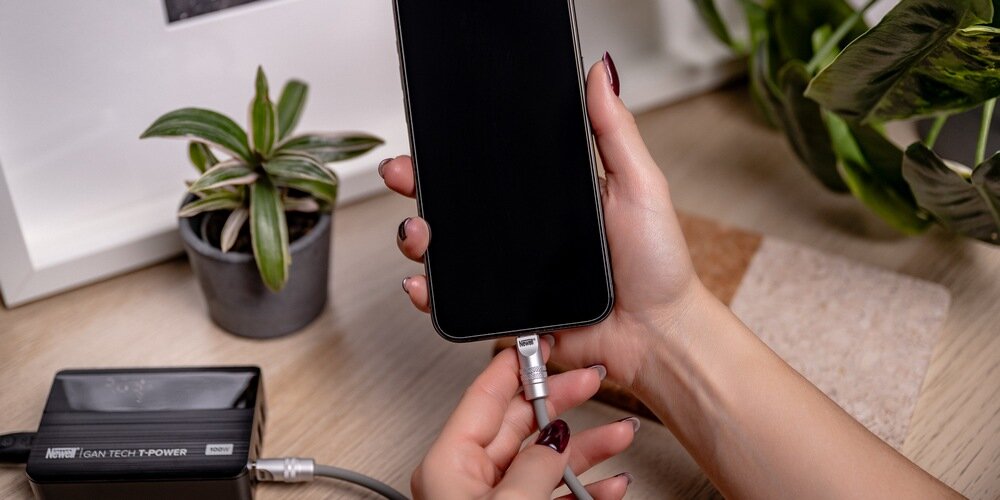 Telefon podłączony  silikonowym kablem Newell USB-C - USB-C 100 W, 2 m do ładowarki marki Newell.