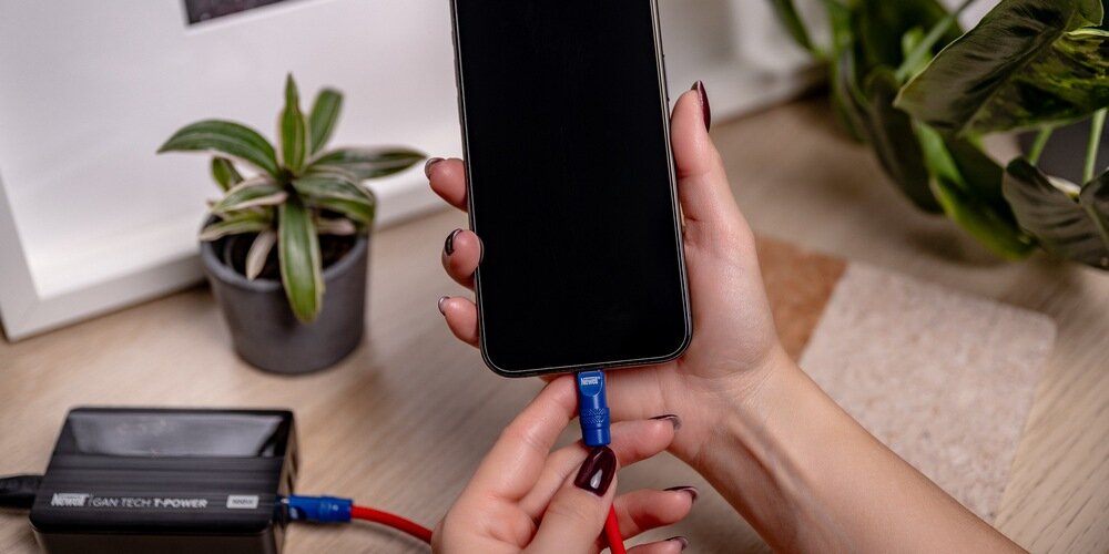Telefon podłączony  silikonowym kablem Newell USB-C - USB-C 100 W, 2 m do ładowarki marki Newell.