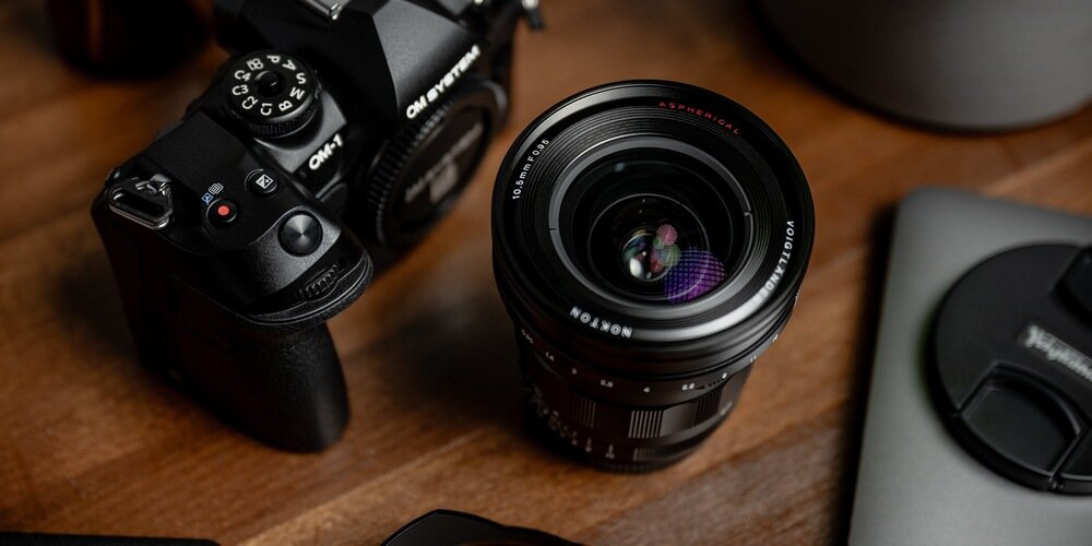 Obiektyw szerokokątny Nokton 10,5 mm f/0,95 MFT na biurku przed zamontowaniem do aparatu zastosowanie osłona przeciwsłoneczna
