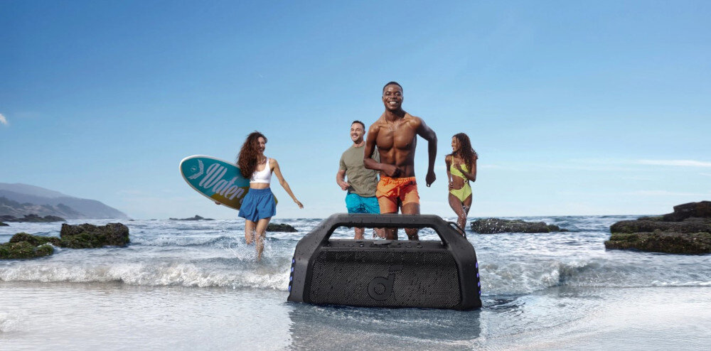 Głośnik mobilny SOUNDCORE Boom 2 Plus z mocnym basem 140 W i technologią BassUp, osoby wychodzące z wody, głośnik stojący w wodzie na brzegu plaży