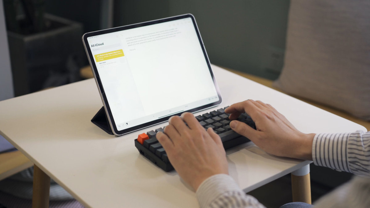 Keychron K12 Profilowane keycapy dwupoziomowe, regulowane nóżki dopasować kąt nachylenia Keychron K12 - klawiatura obok tabletu, używana przez kogoś