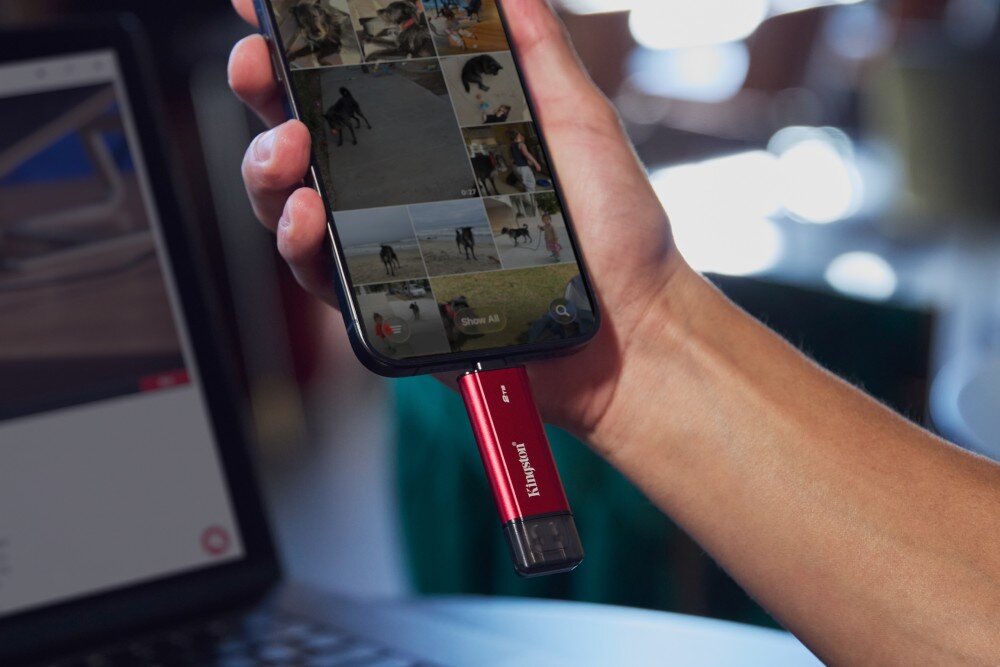Dysk KINGSTON Dual Portable Dłoń trzyma telefon, do którego dolnego portu podłączone jest małe, podłużne urządzenie z napisami 'Kingston' i '2 TB', cechy, wygląd