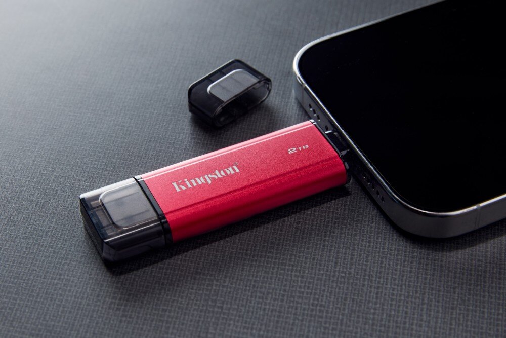 Dysk KINGSTON Dual Portable Małe, podłużne urządzenie z napisami 'Kingston' i '2 TB' jest wpięte do portu na boku smartfona, obok leży jedna zatyczka, pojemność, przeznaczenie