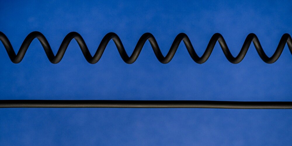  kabel Newell USB-C - USB-C 100 W, 1,5m w dwóch wersjach: spiralnej, pod nią wyprostowanej, na niebieskim tle.