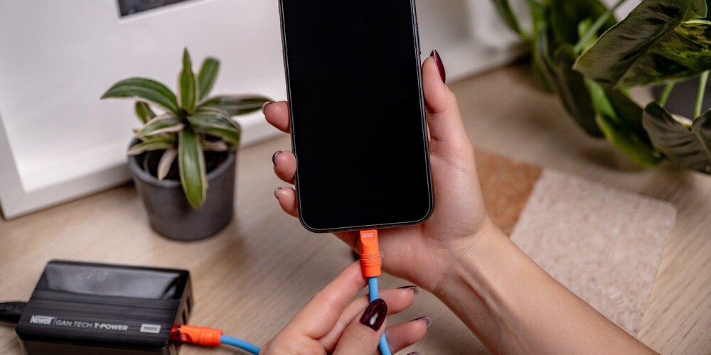 Damskie dłonie podłączają telefon  kablem Newell USB-C - USB-C 100 W, 1,5m do ładowarki.