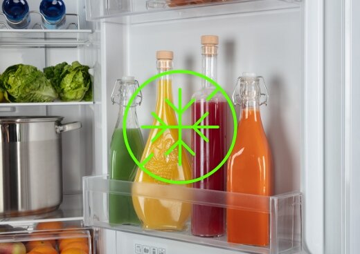 Zbliżenie na drzwi lodówki, na których są butelki z napojami. Płatek śniegu jako oznaczenie systemu Total No Frost.