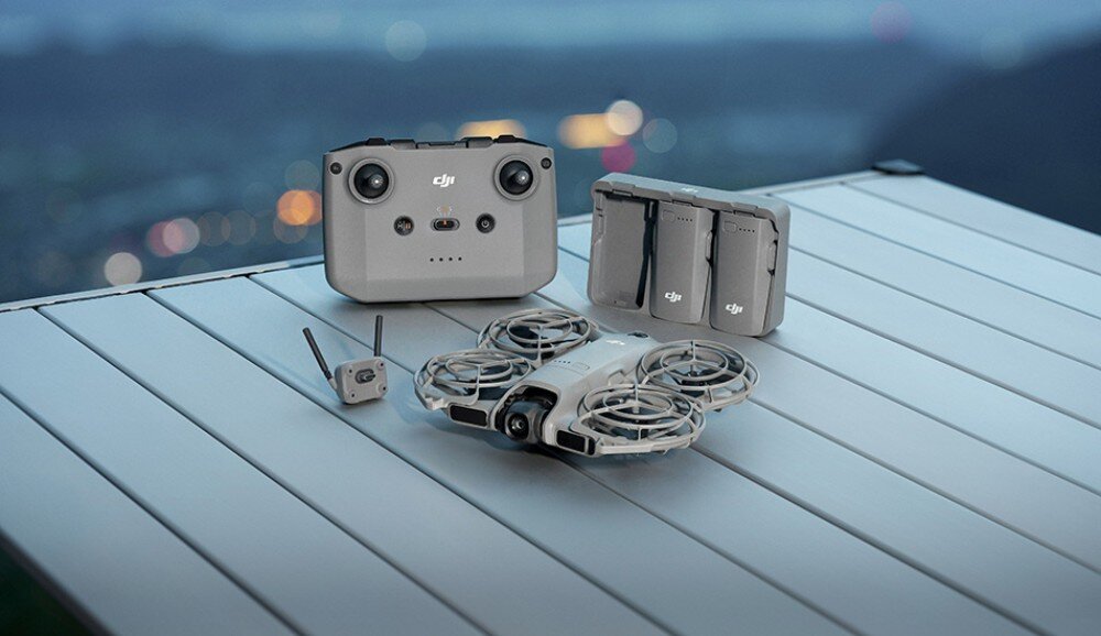 Dron DJI Neo 2 Fly More Combo Zestaw akcesoriów z kontrolerem, dwiema bateriami, ładowarką, przewodami i małym dronem ułożony na jasnym blacie, zestaw, akcesoria