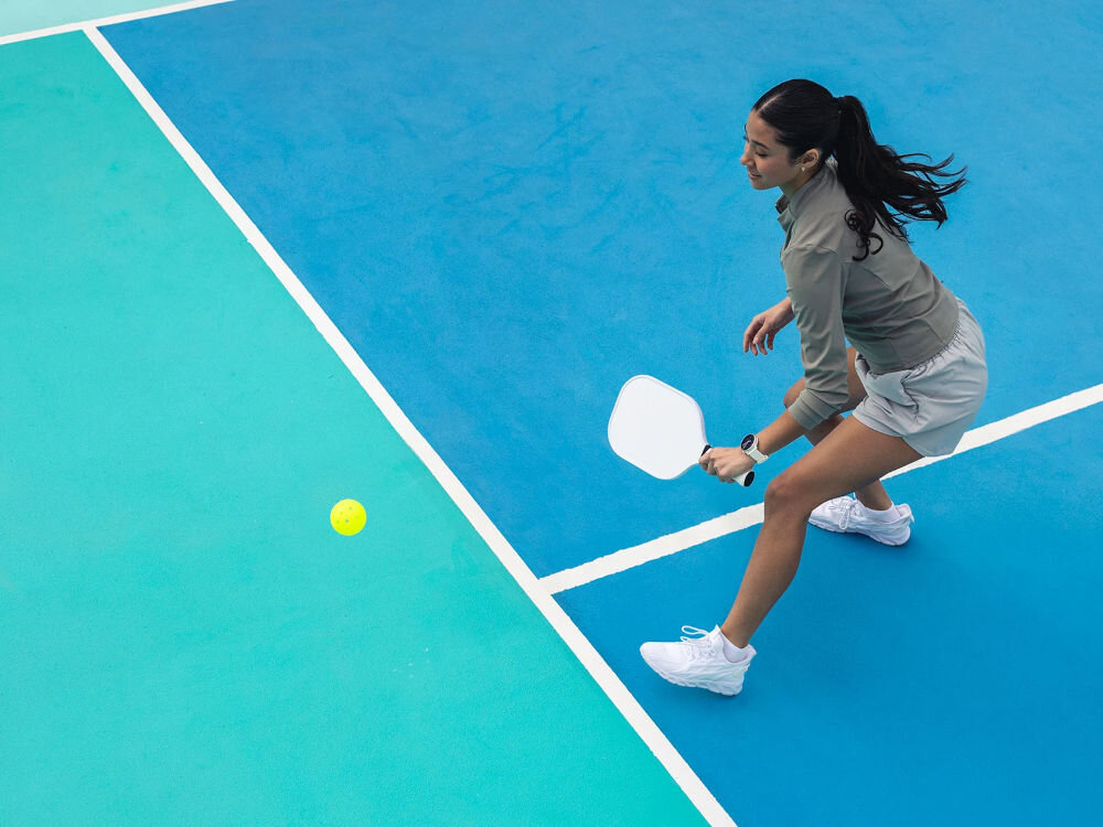 Zegarek sportowy GARMIN Vivoactive 6 osoba grająca w tenisa ziemnego z zegarkiem na ręku wyświetlacz AMOLED 1,2 Corning® Gorilla® Glass 3 anodyzowana ramka działanie do 11 dni